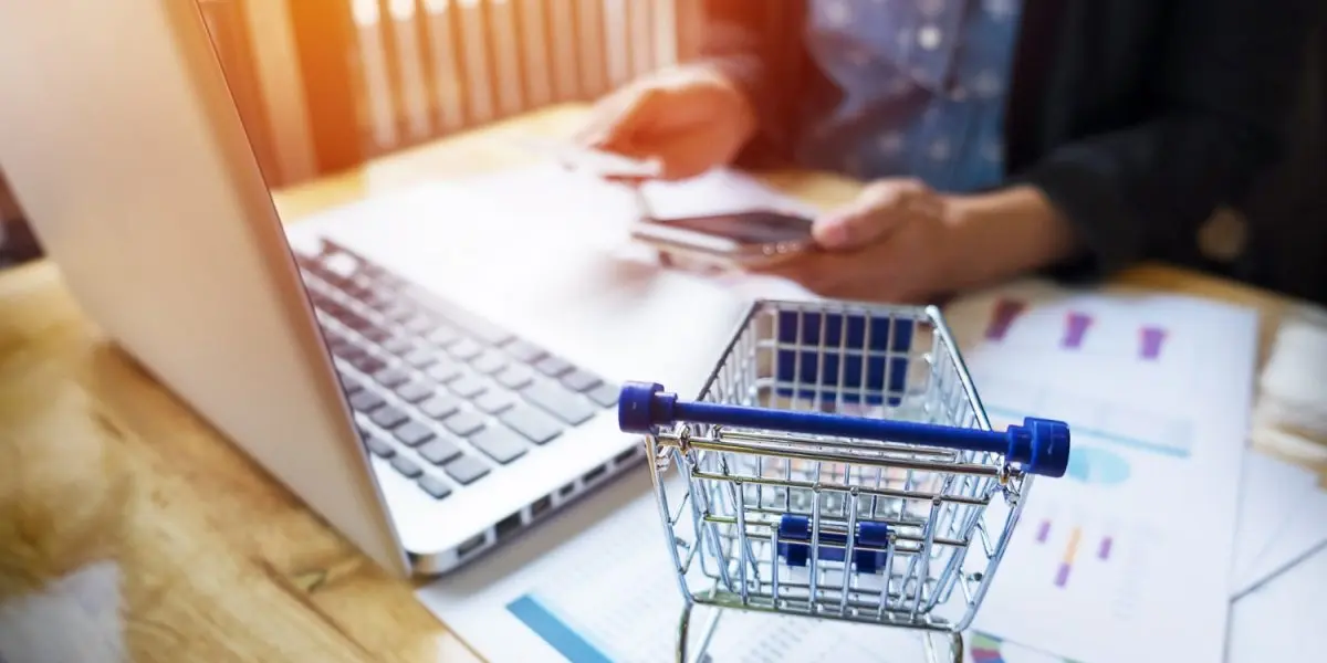 Person setting up a WooCommerce affiliate program on a laptop with ecommerce analytics reports