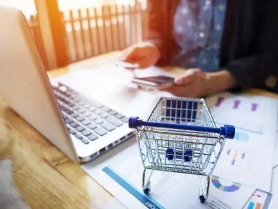 Person setting up a WooCommerce affiliate program on a laptop with ecommerce analytics reports