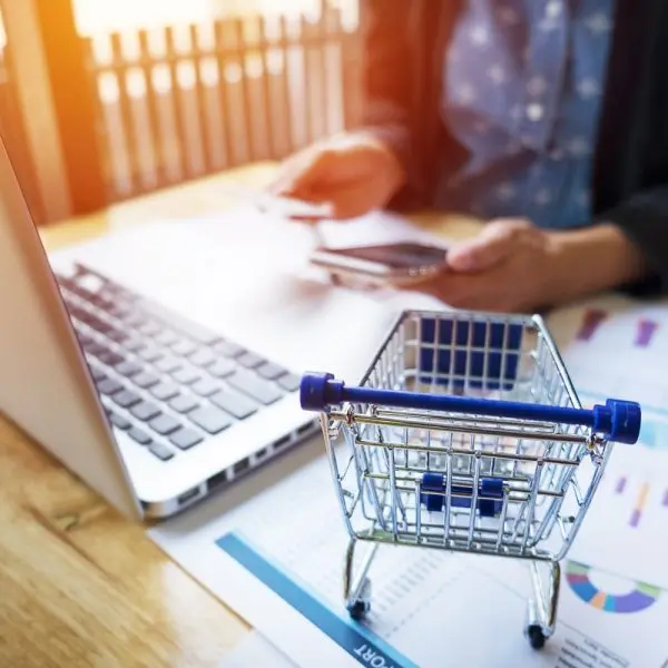 Person setting up a WooCommerce affiliate program on a laptop with ecommerce analytics reports