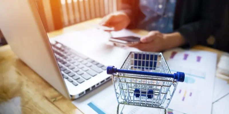 Person setting up a WooCommerce affiliate program on a laptop with ecommerce analytics reports